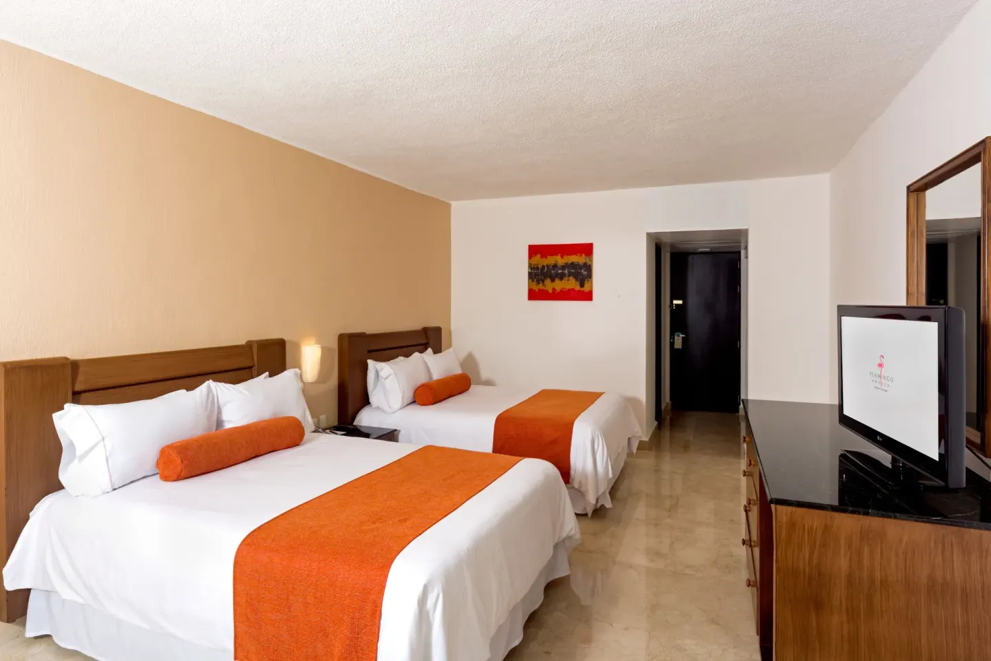 Guest room with two beds, orange accents, and TV dresser at Flamingo Cancun.