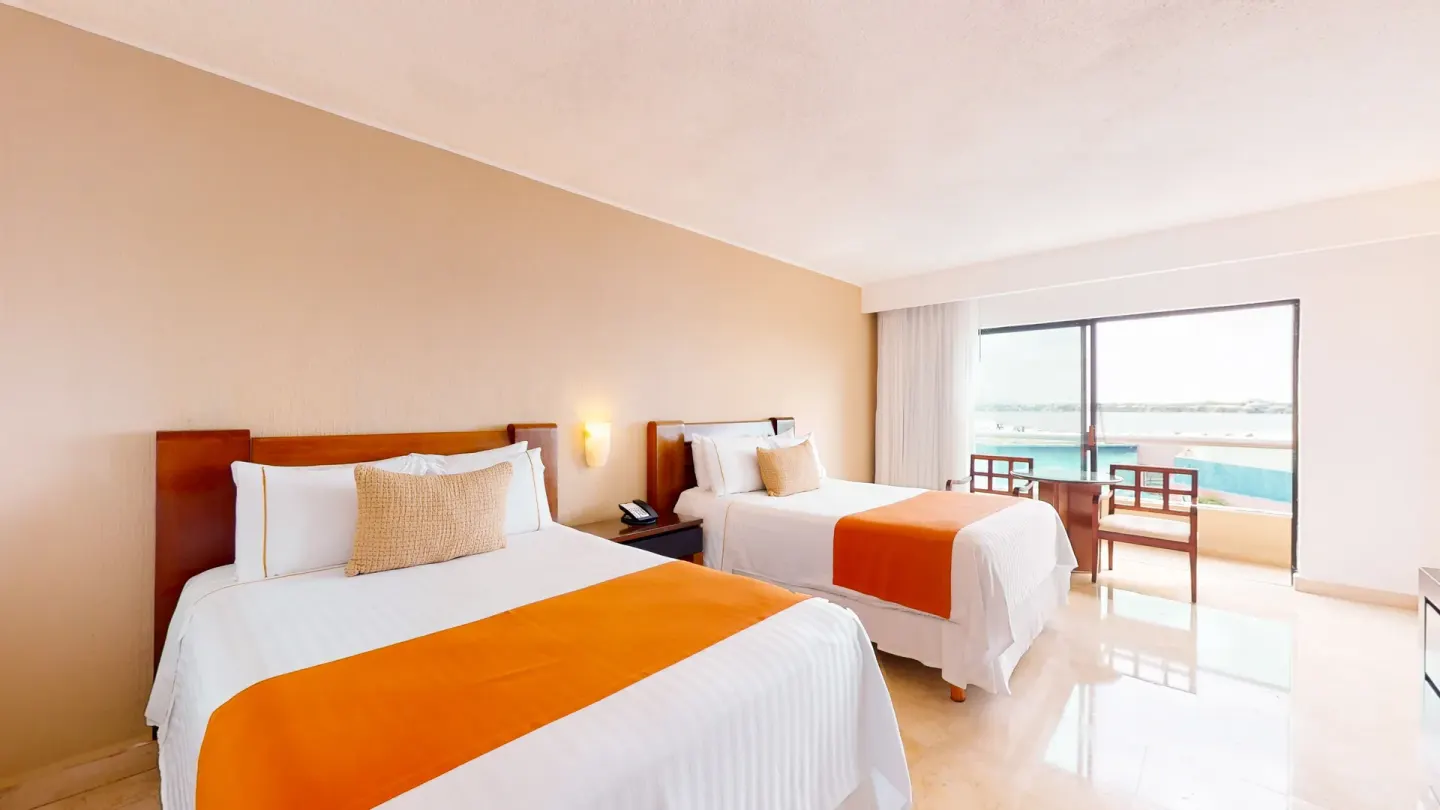 Two-bed guest room with balcony and water view at Flamingo Cancun.