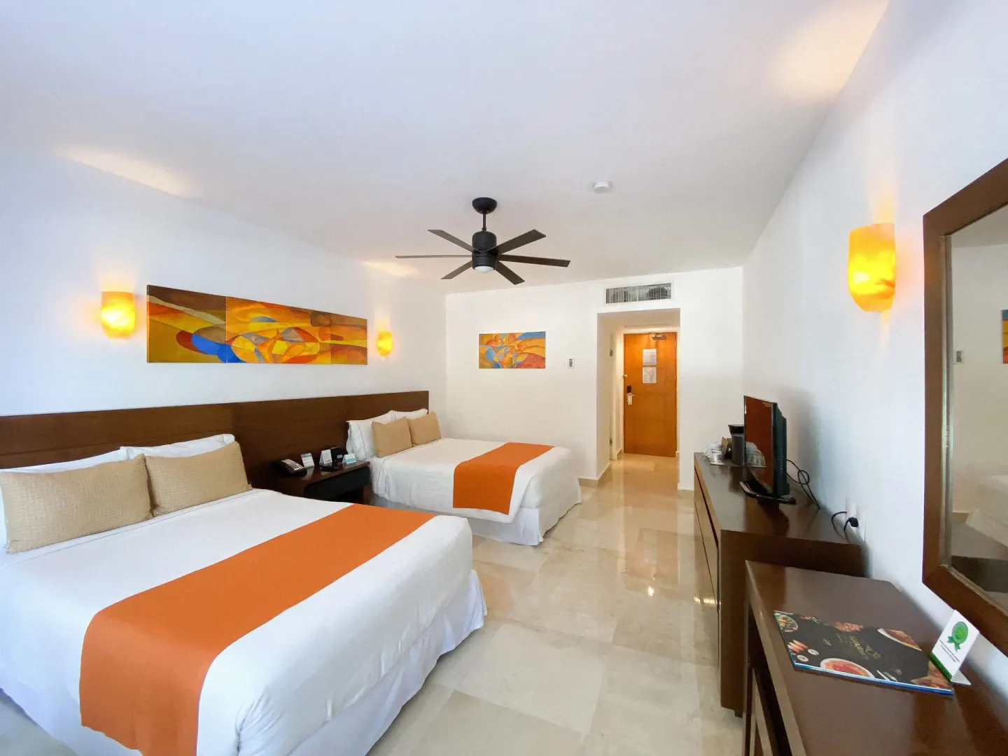 Guest room with two double beds and orange accents at Flamingo Cancun.