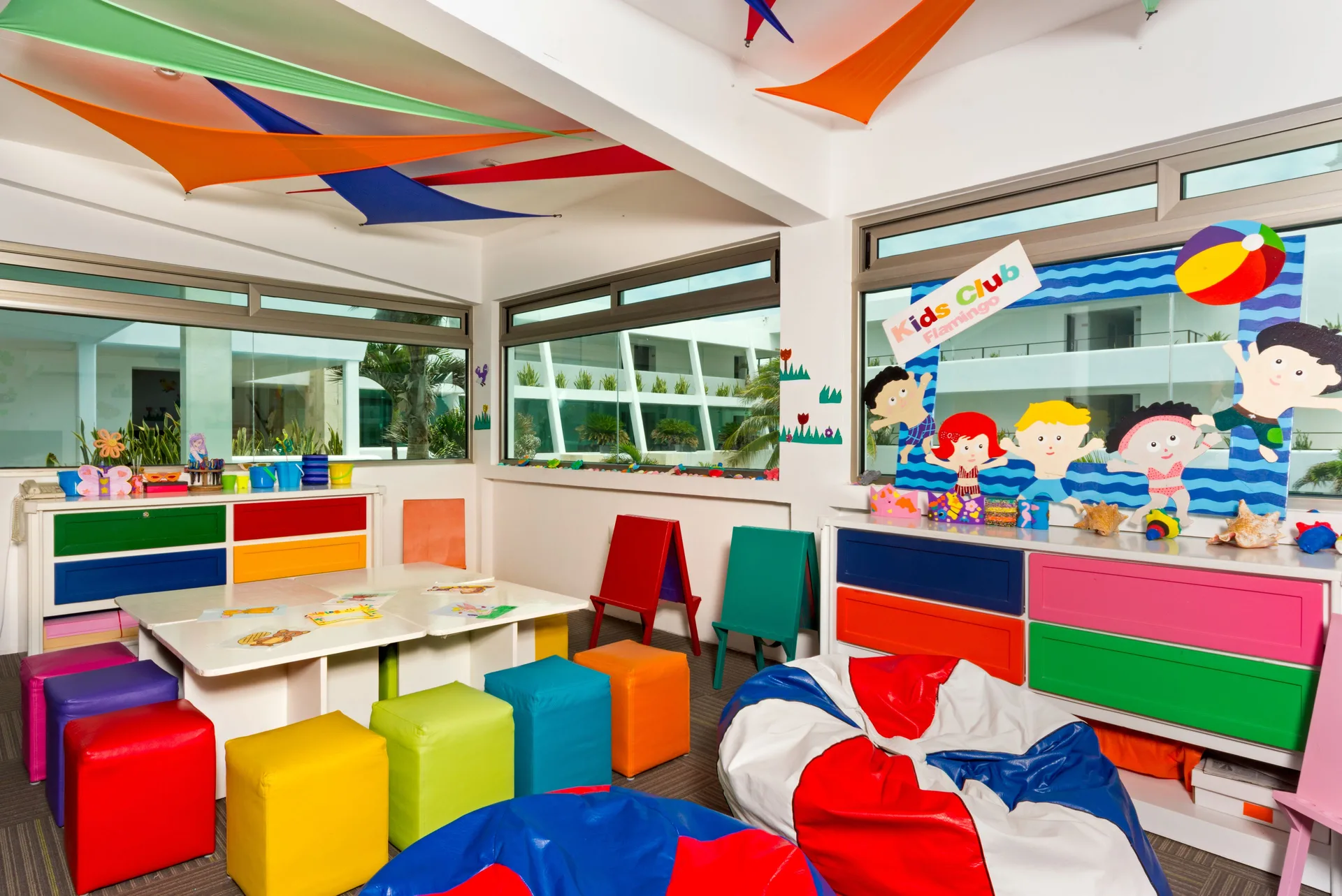 Colorful kids club playroom with tables, stools, beanbags, and wall art at Flamingo Cancun.