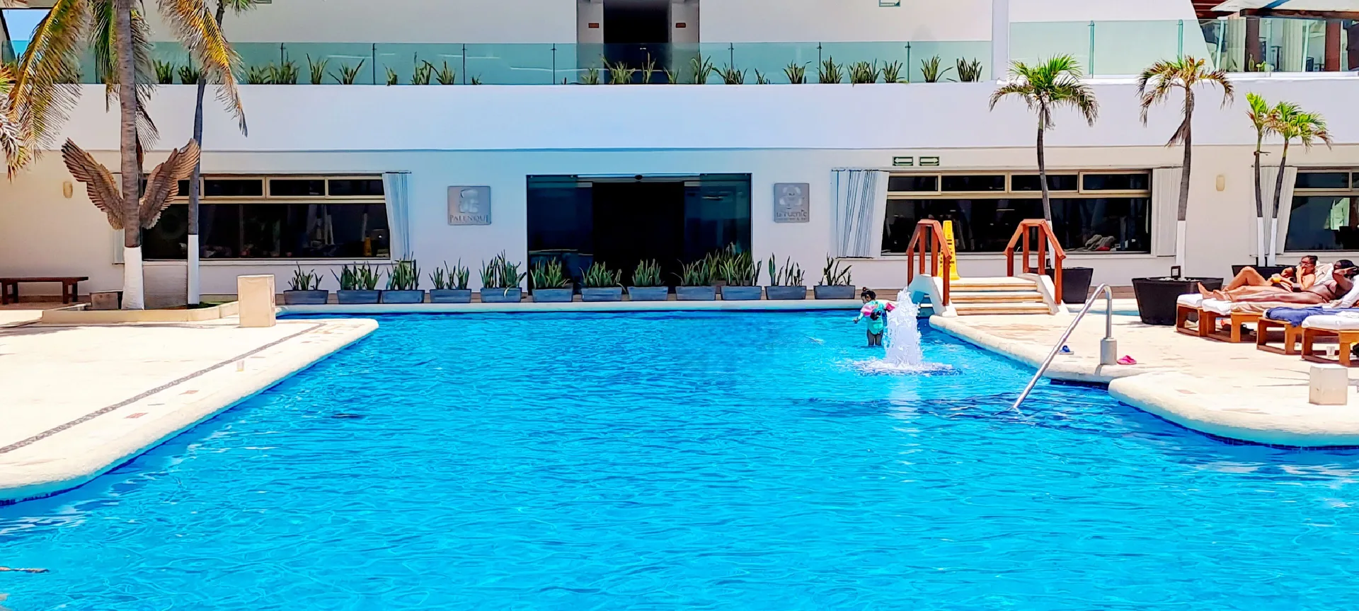 Main pool with bridge, loungers, and resort façade at Flamingo Cancun.