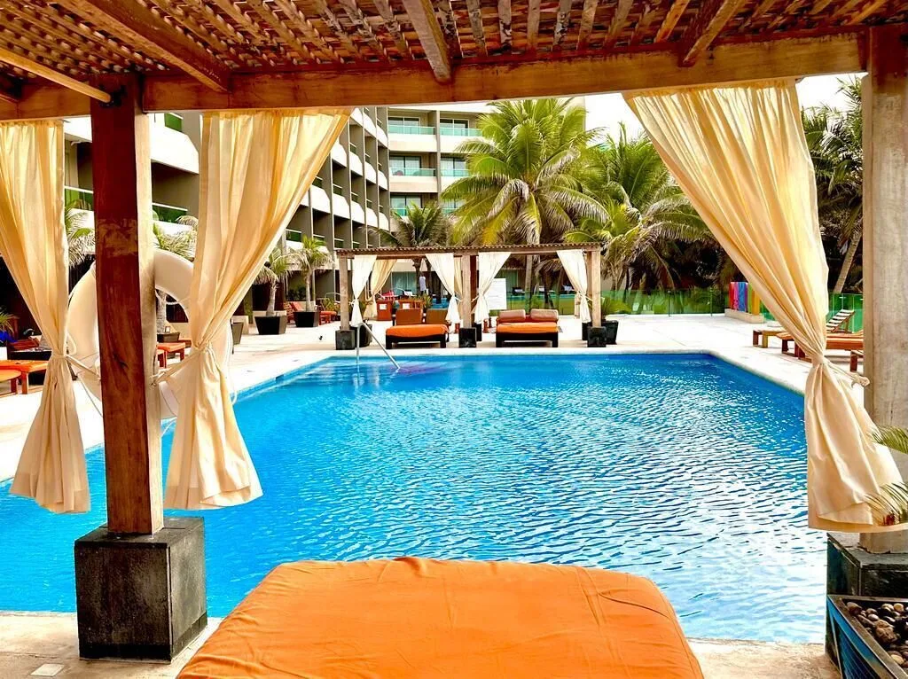 Poolside cabana with orange cushion overlooking the pool at Flamingo Cancun.