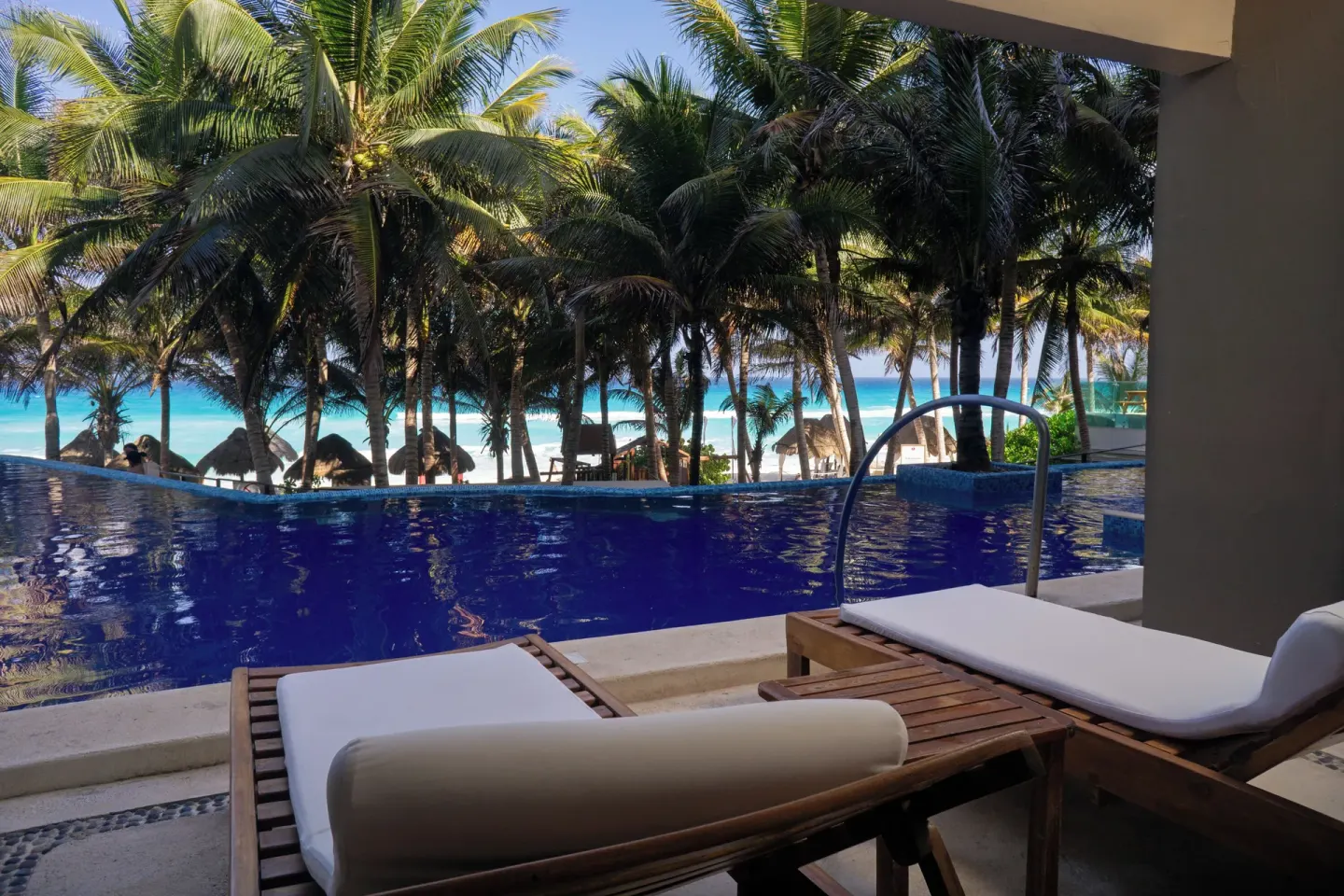 Poolside loungers facing palms and the beach at Flamingo Cancun.