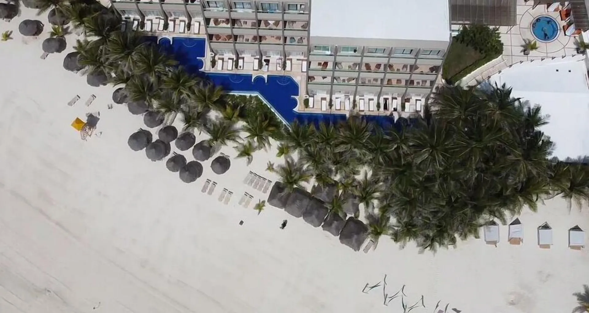 Top-down view of beachfront palms, pools, and sand at Flamingo Cancun.
