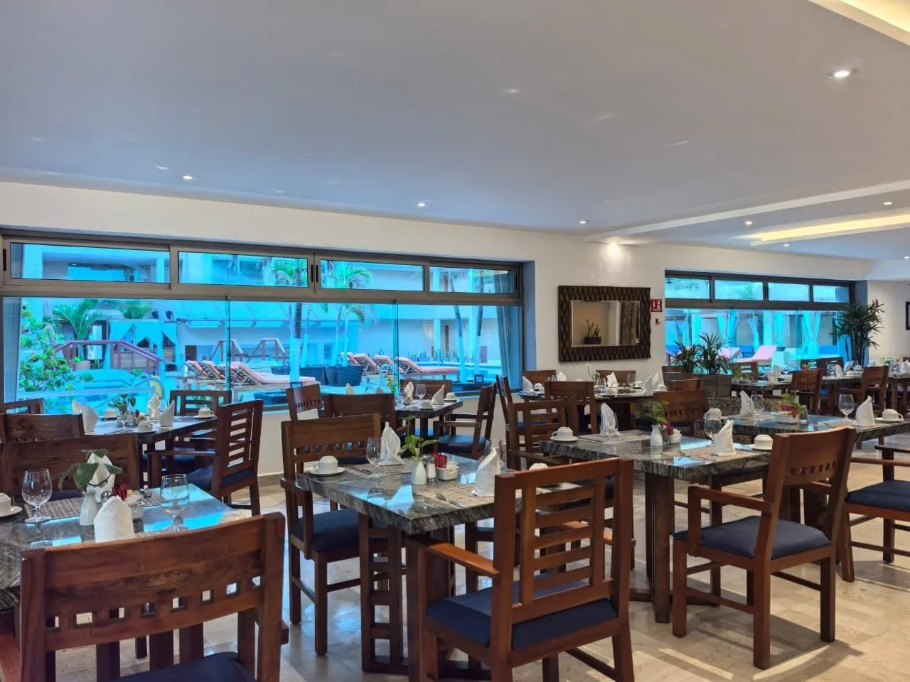 Indoor restaurant dining room with set tables and pool-facing windows at Flamingo Cancun.