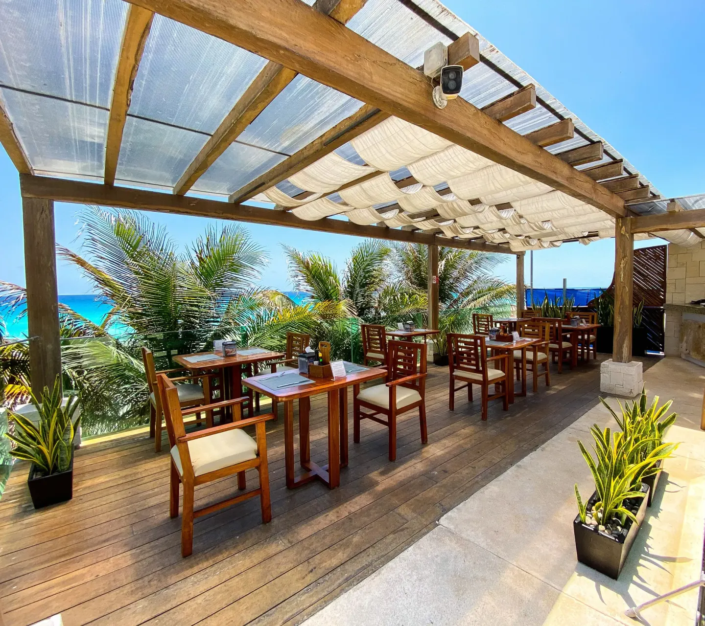 Oceanfront terrace dining tables beneath a pergola at Flamingo Cancun.