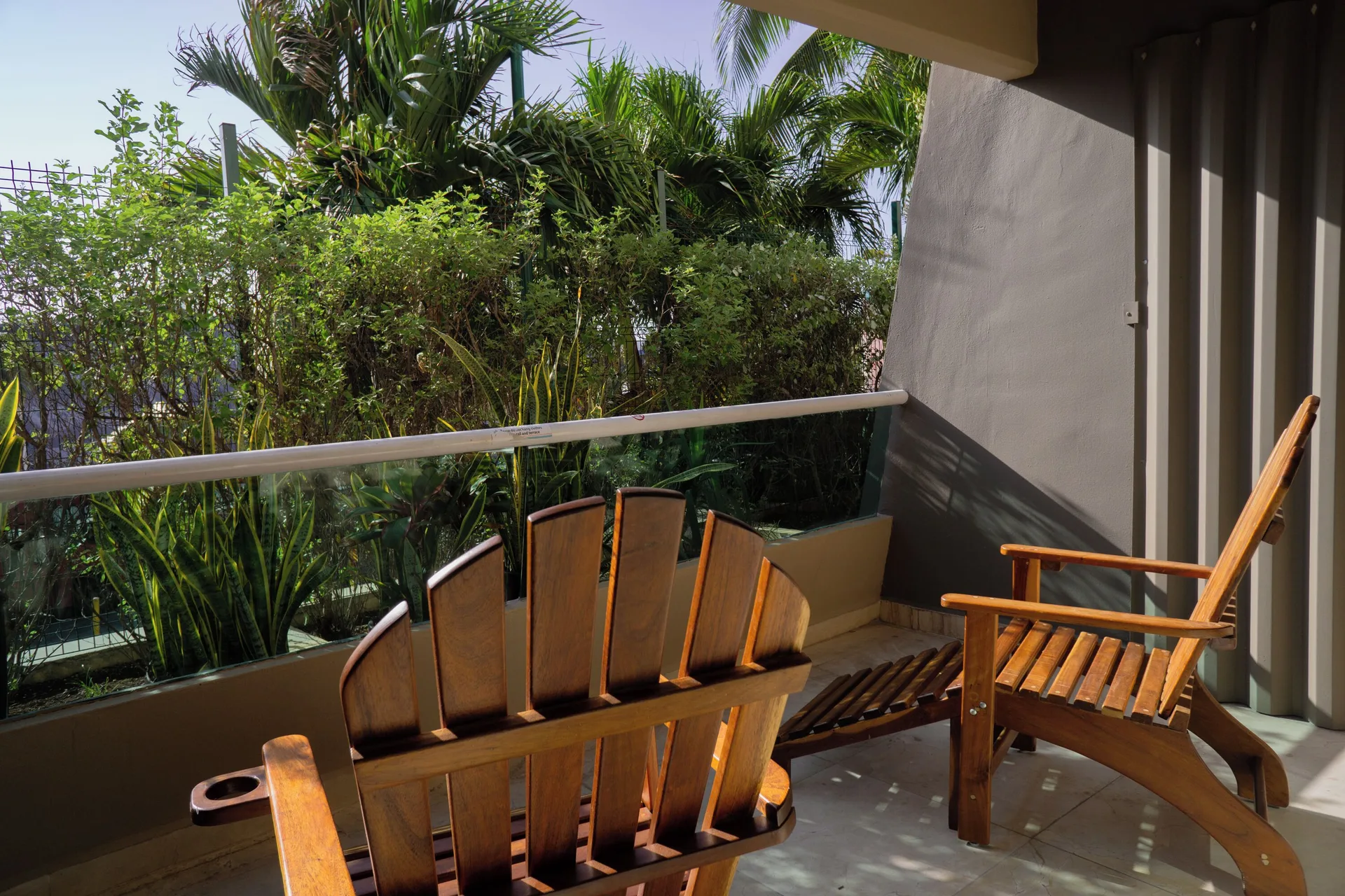 Family Room balcony at Flamingo Cancun with wooden chairs and tropical greenery.