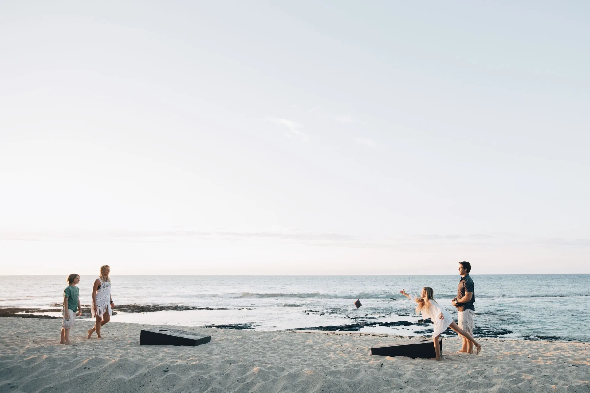 Guests play cornhole on the sandy beach at Four Seasons Resort Hualalai.