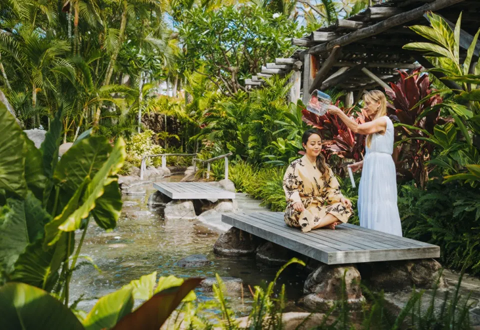 Spa attendant pouring water over a seated guest at Four Seasons Resort Hualalai.