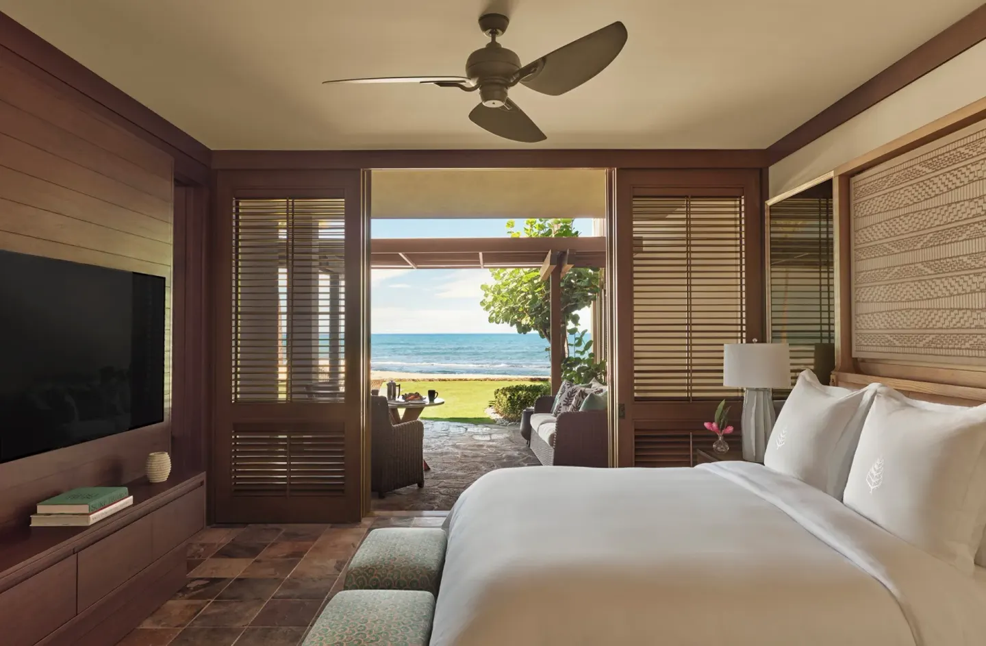 King bedroom opening to a ground-floor oceanfront patio at Four Seasons Resort Hualalai.