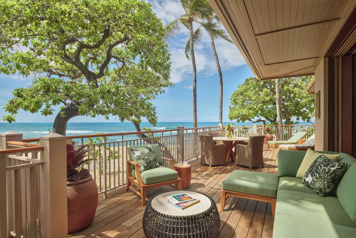 Ocean-view lanai with green seating and dining table at Four Seasons Resort Hualalai.