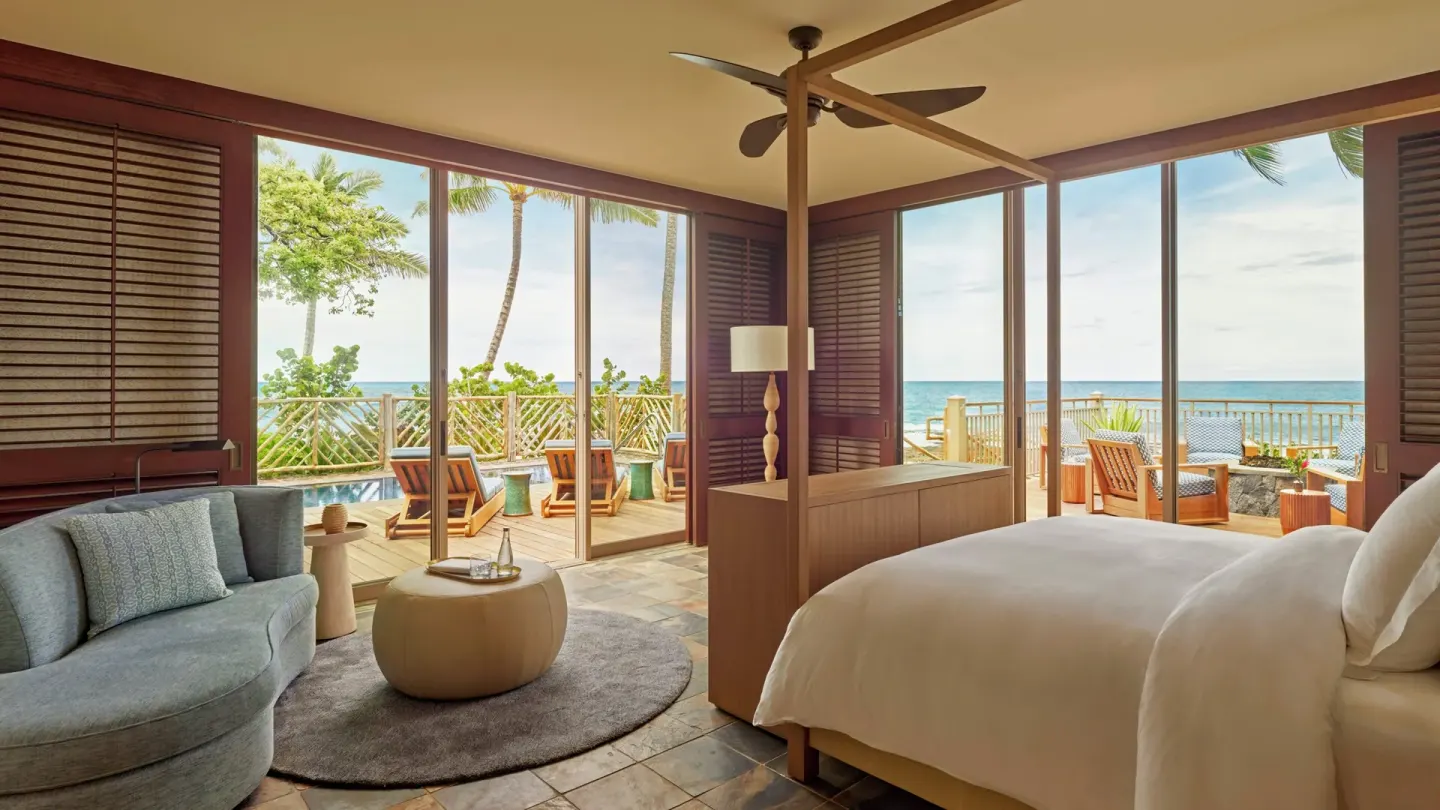 Oceanfront bedroom with king bed, sitting area, and wraparound lanai at Four Seasons Resort Hualalai.