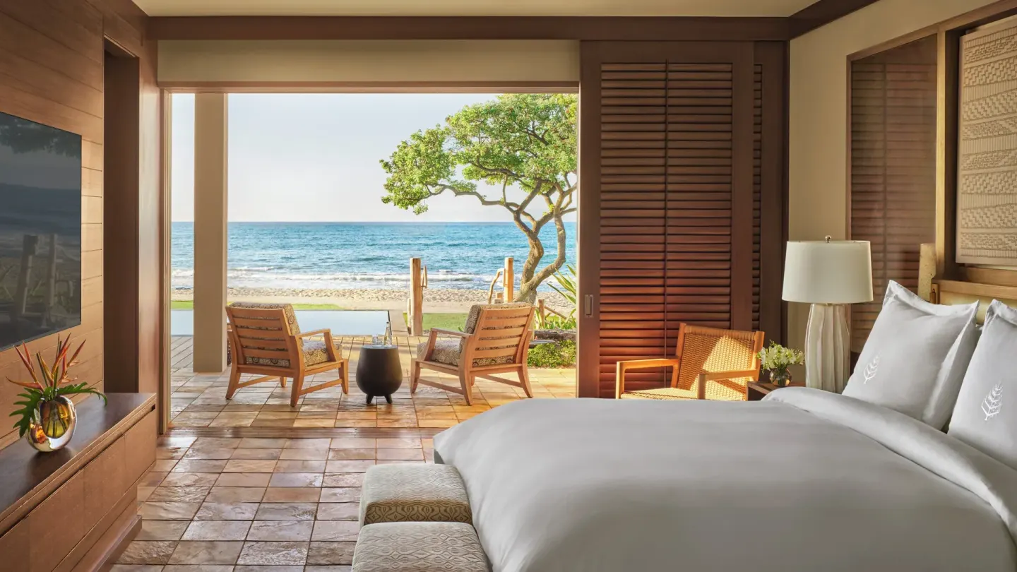 Oceanfront guest room with king bed and patio at Four Seasons Resort Hualalai.