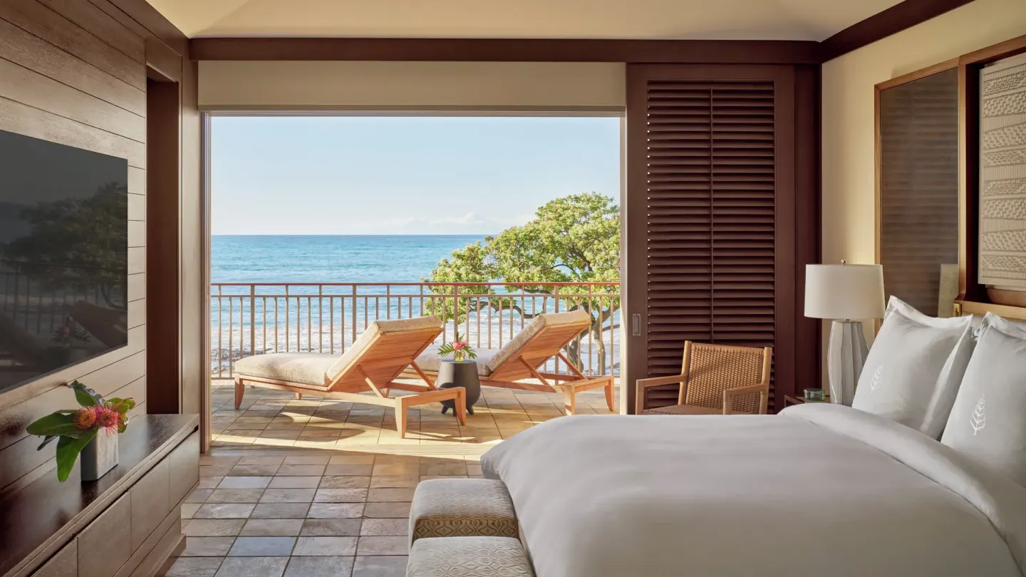 Oceanfront king guest room with lanai and chaise lounges at Four Seasons Resort Hualalai.