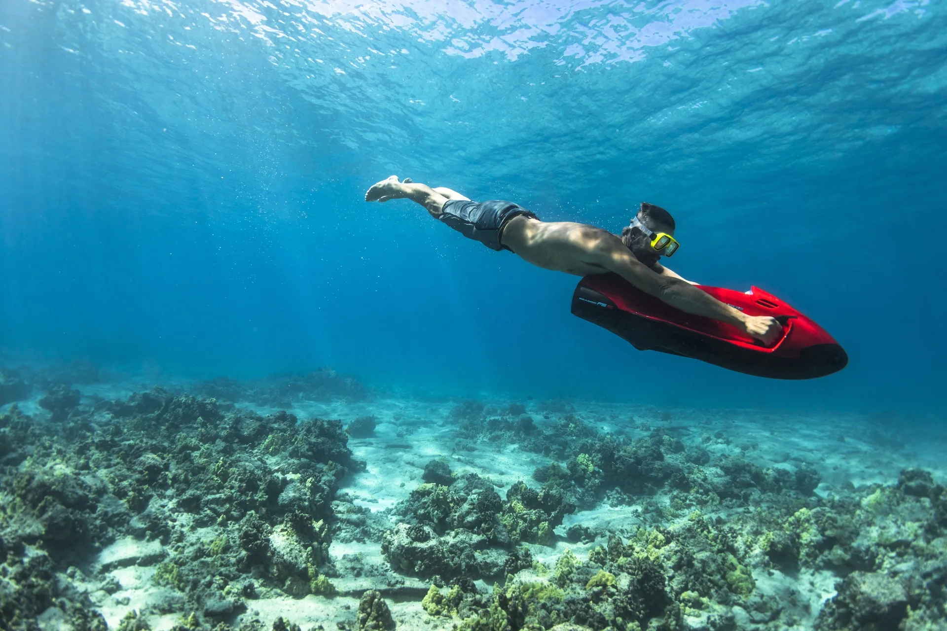 Snorkeler using a red sea scooter over coral at Four Seasons Resort Hualalai.