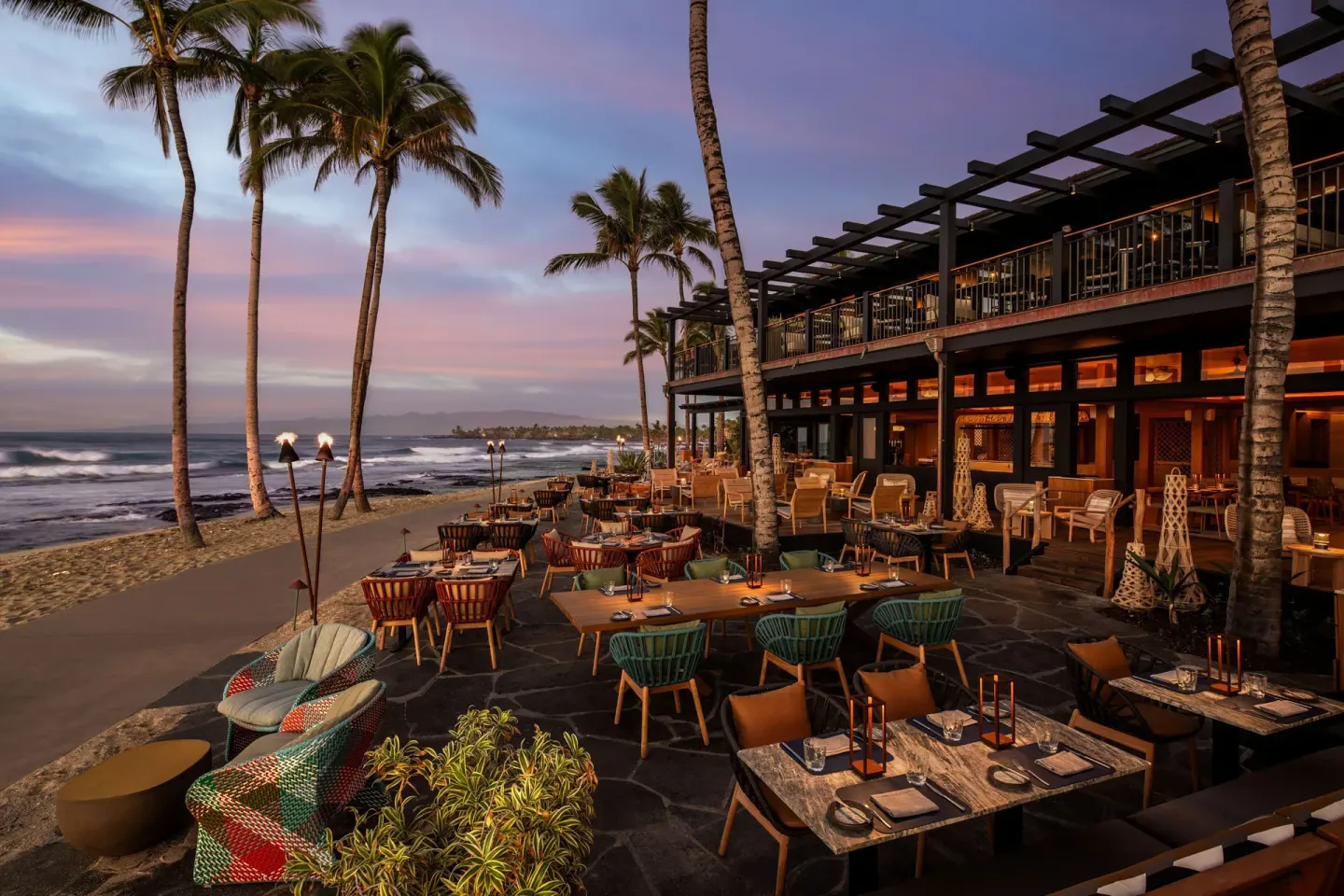 Beachfront restaurant terrace with palms at dusk at Four Seasons Resort Hualalai.