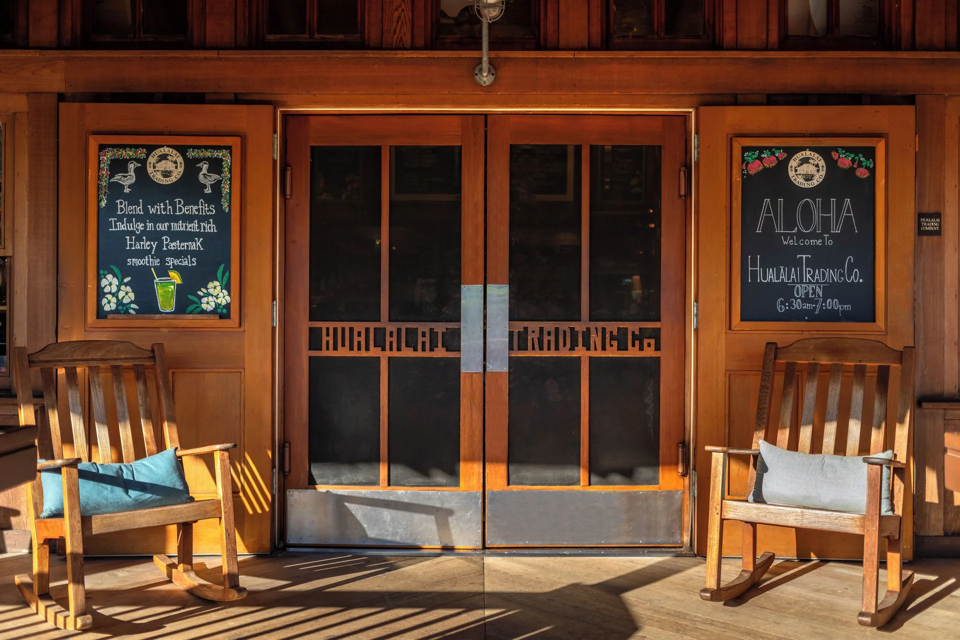 Hualalai Trading Company entrance at Four Seasons Resort Hualalai with chalkboard signs and rocking chairs.
