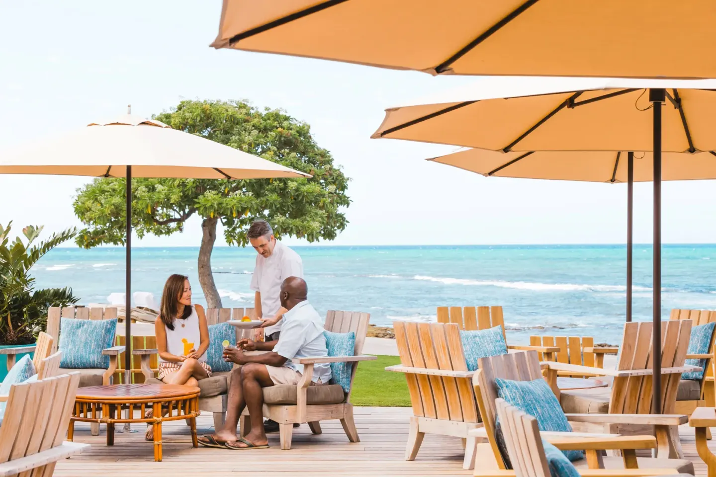 Guests are served drinks on an oceanfront deck at Four Seasons Resort Hualalai.