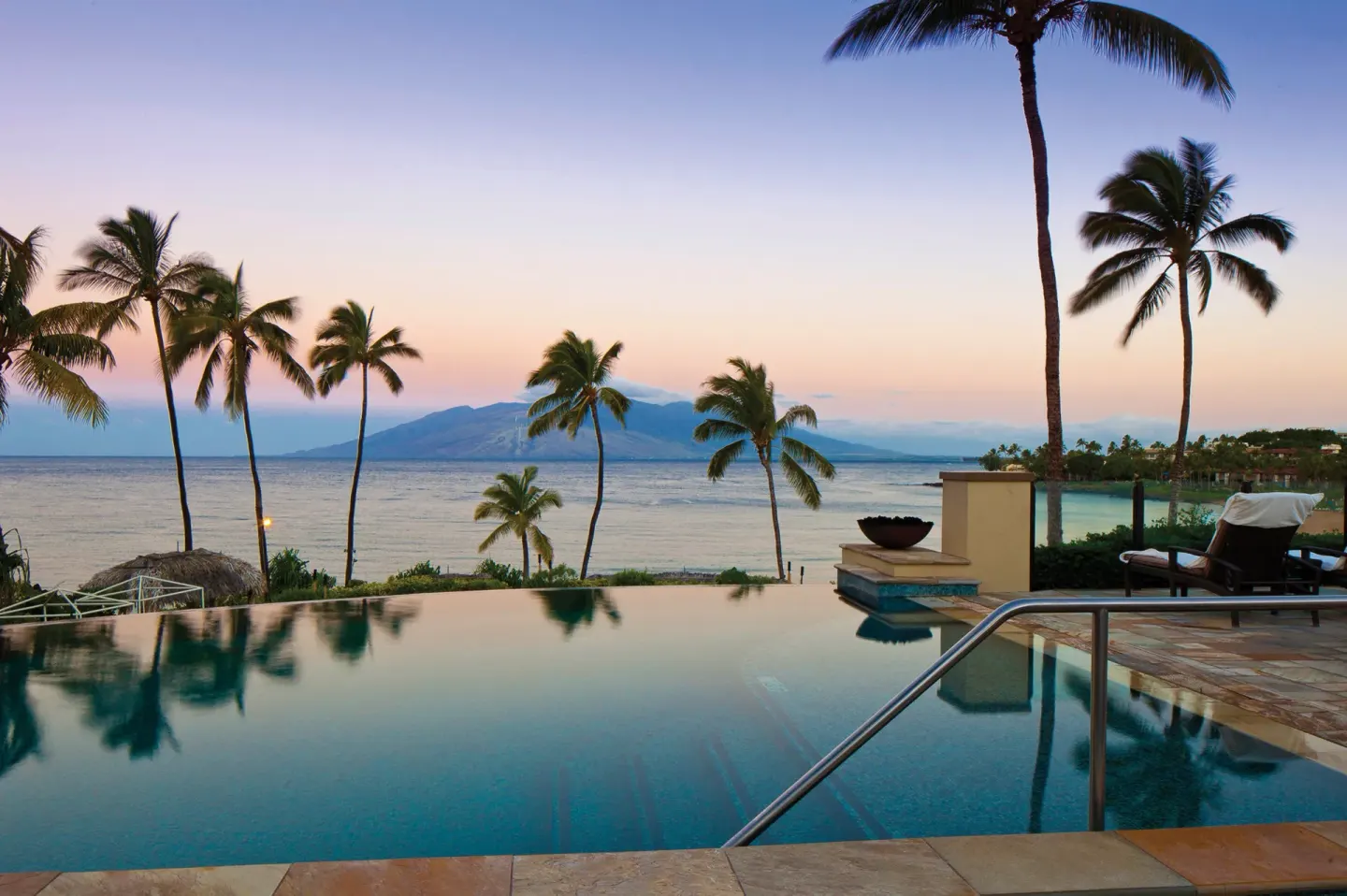 Infinity pool and palm trees frame the ocean at Four Seasons Resort Maui at Wailea.