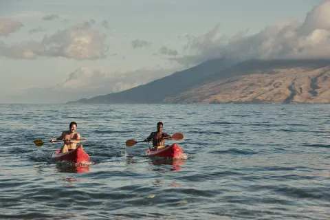 Two kayakers paddle on the ocean near Four Seasons Resort Maui at Wailea.