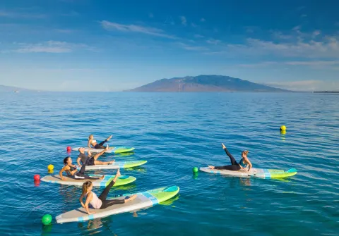 Guests doing paddleboard fitness on the ocean at Four Seasons Resort Maui at Wailea.