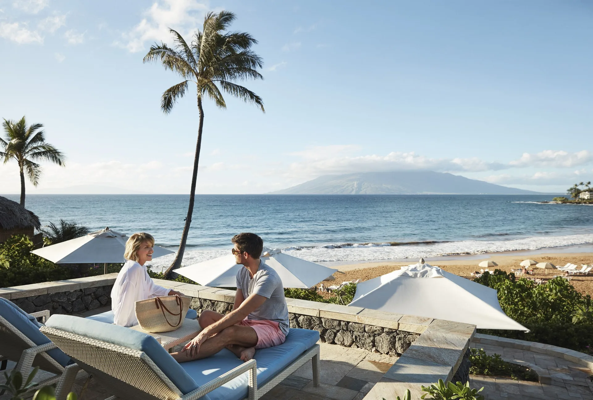 Guests relax on oceanfront loungers at Four Seasons Resort Maui at Wailea.