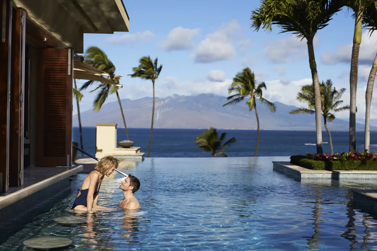 Couple in an oceanview pool beside palms at Four Seasons Resort Maui at Wailea.