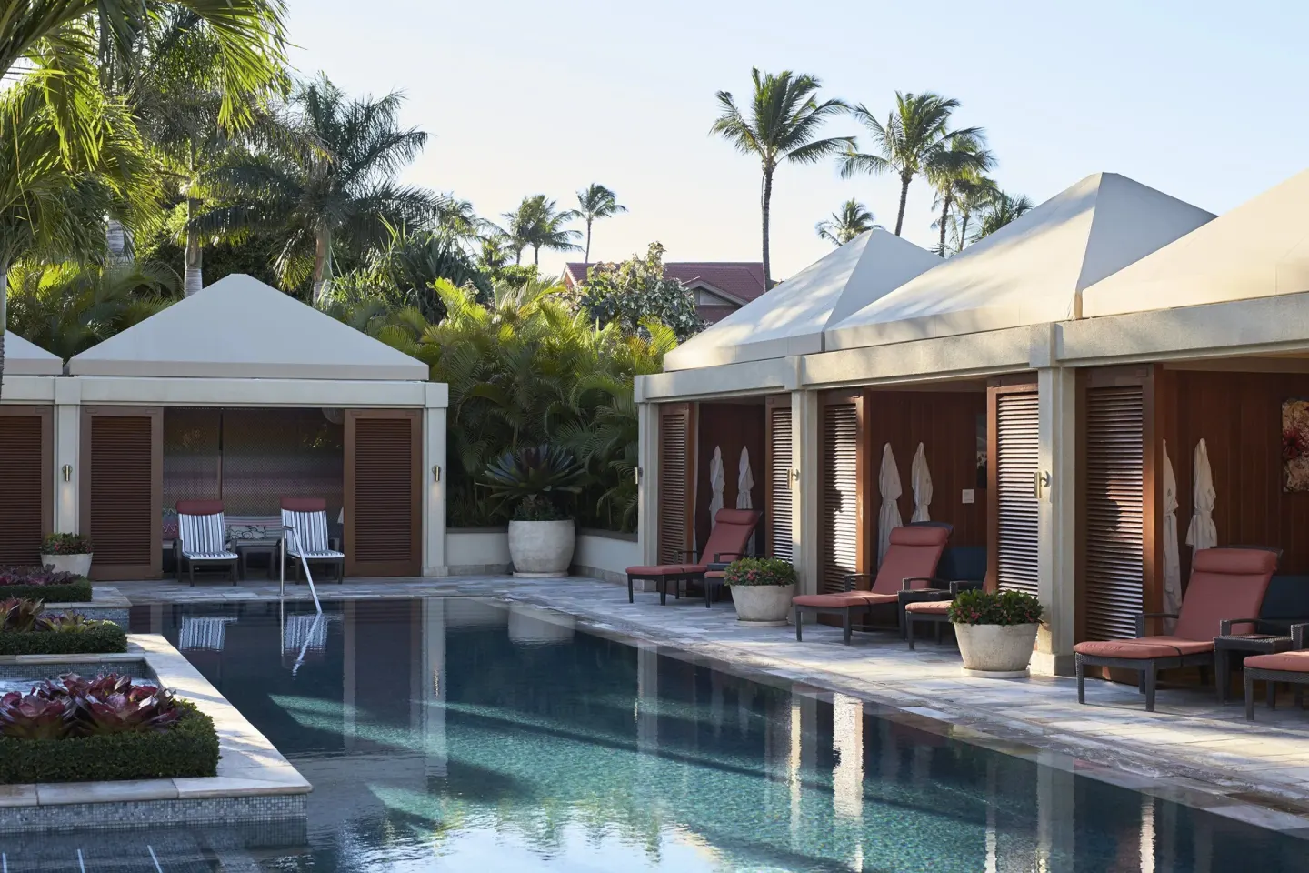 Private cabanas and lounge chairs beside a pool at Four Seasons Resort Maui at Wailea.