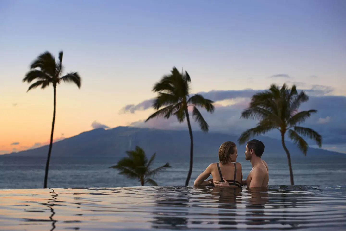Couple in an infinity pool at sunset at Four Seasons Resort Maui at Wailea.