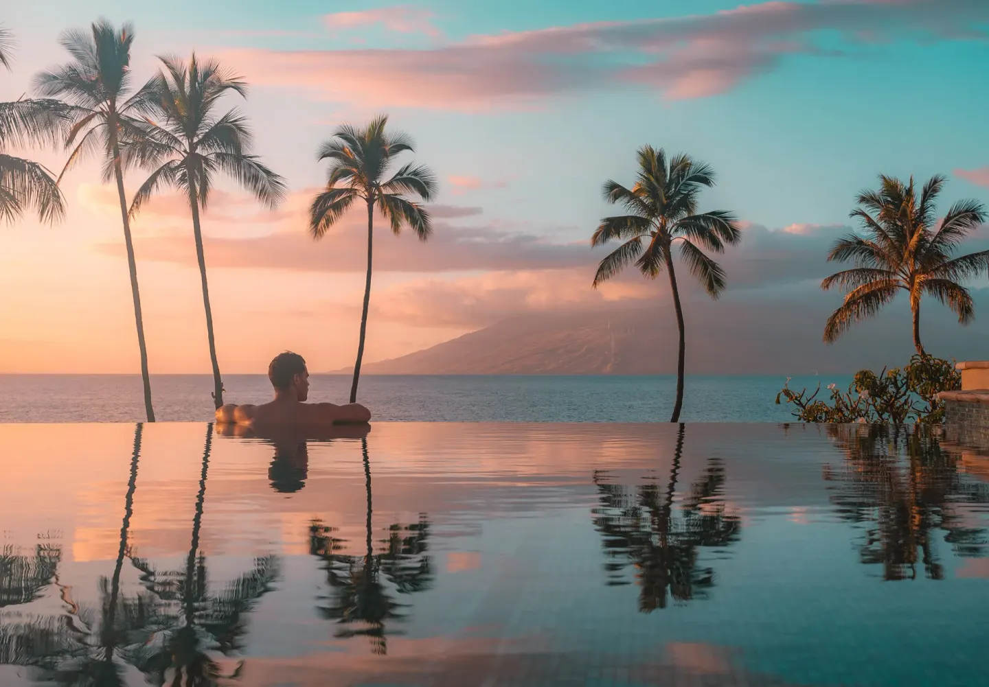 Guest in an infinity pool at sunset at Four Seasons Resort Maui at Wailea.