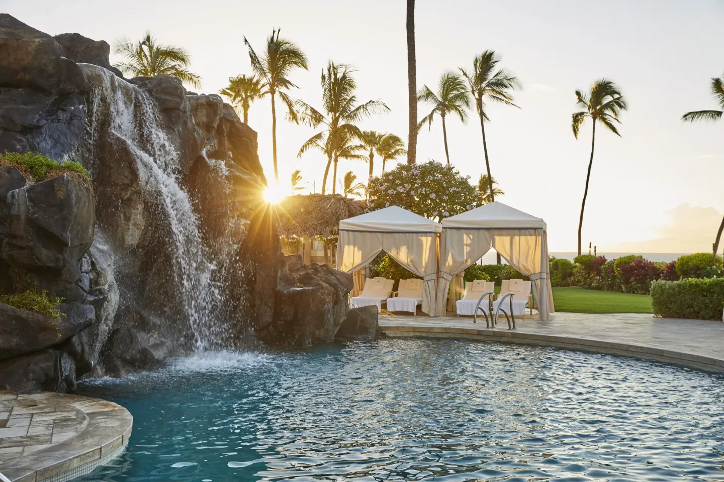 Waterfall pool with cabanas at sunset at Four Seasons Resort Maui at Wailea.