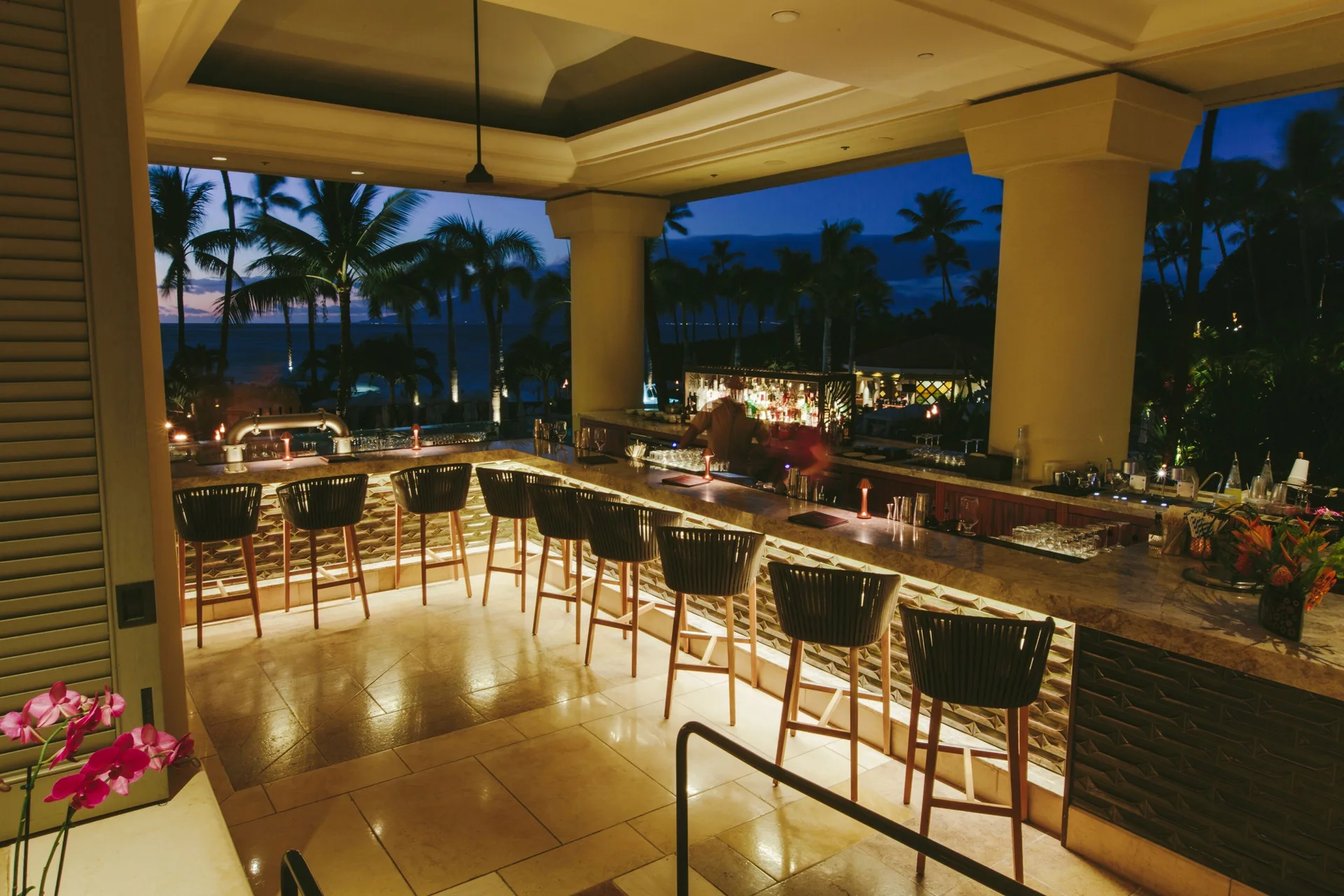 Open-air evening bar with ocean and palms at Four Seasons Resort Maui at Wailea.