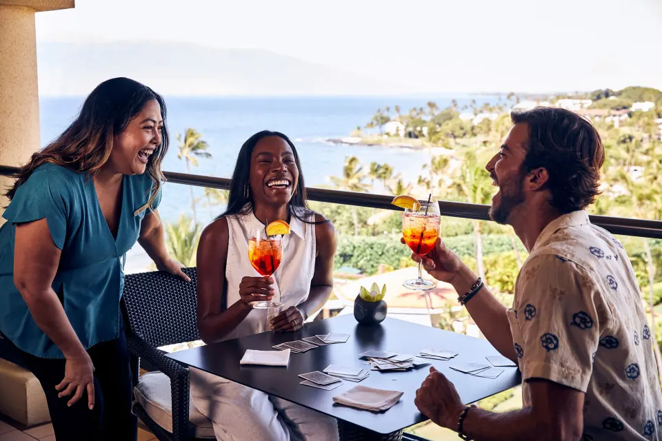 Guests enjoying drinks on a Club Ocean Front One Bedroom Suite lanai at Four Seasons Resort Maui at Wailea.