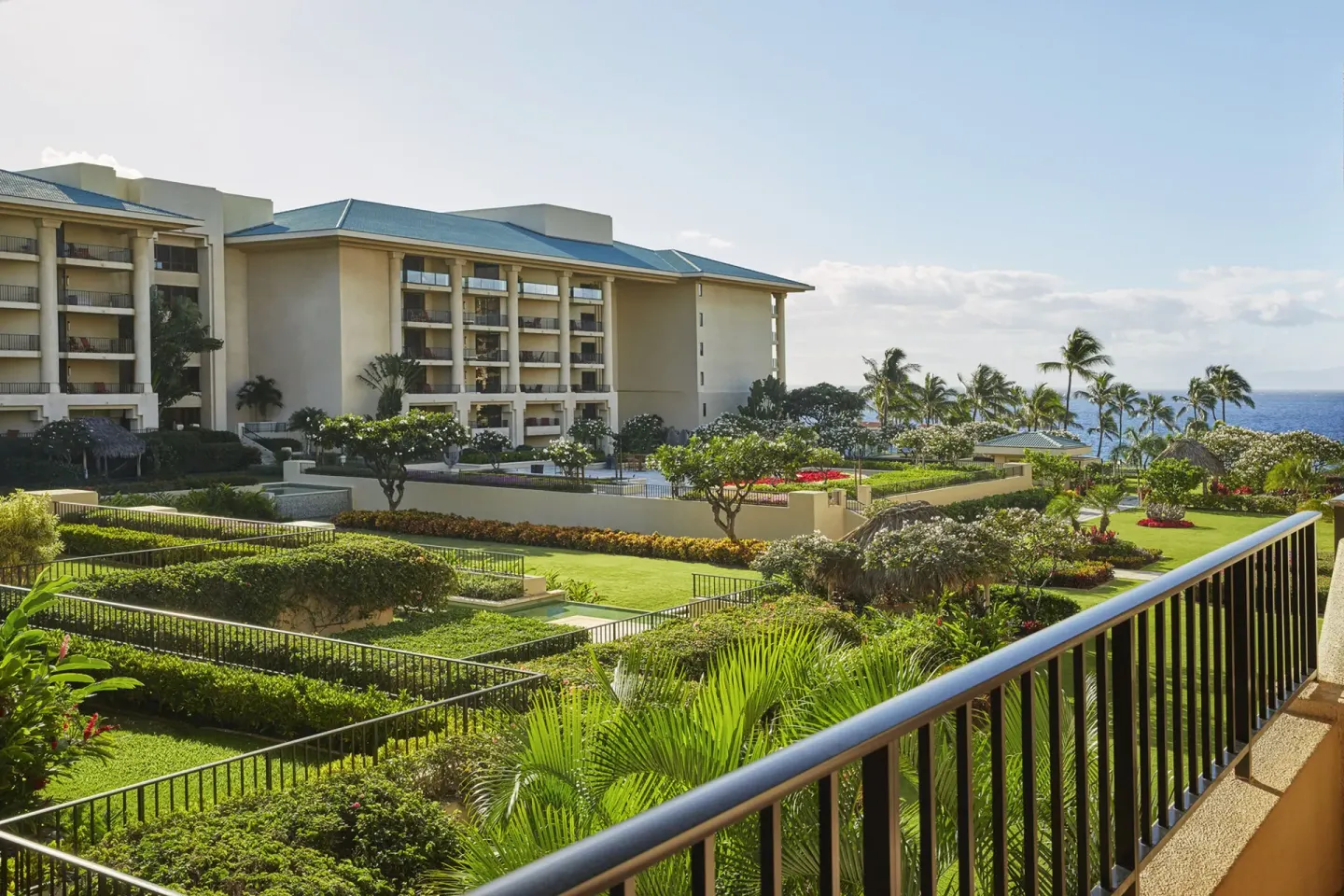 Deluxe Garden View Room balcony overlooking gardens, buildings and ocean at Four Seasons Resort Maui at Wailea.