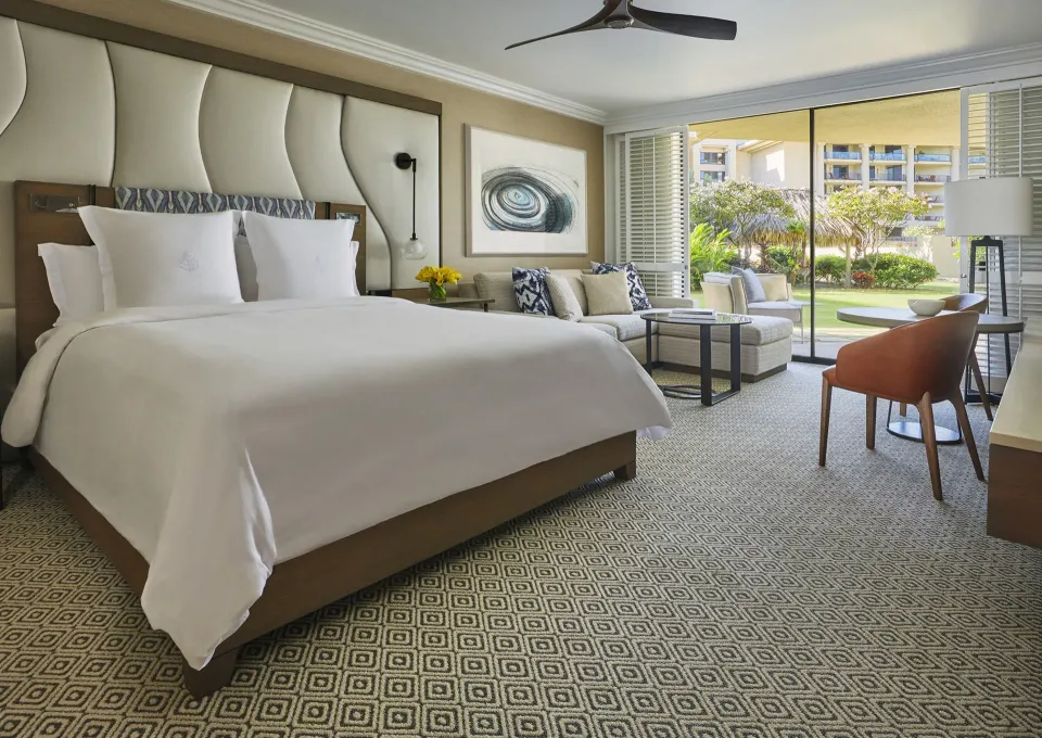 Garden View Room king bed at Four Seasons Resort Maui at Wailea with seating and patio beyond.