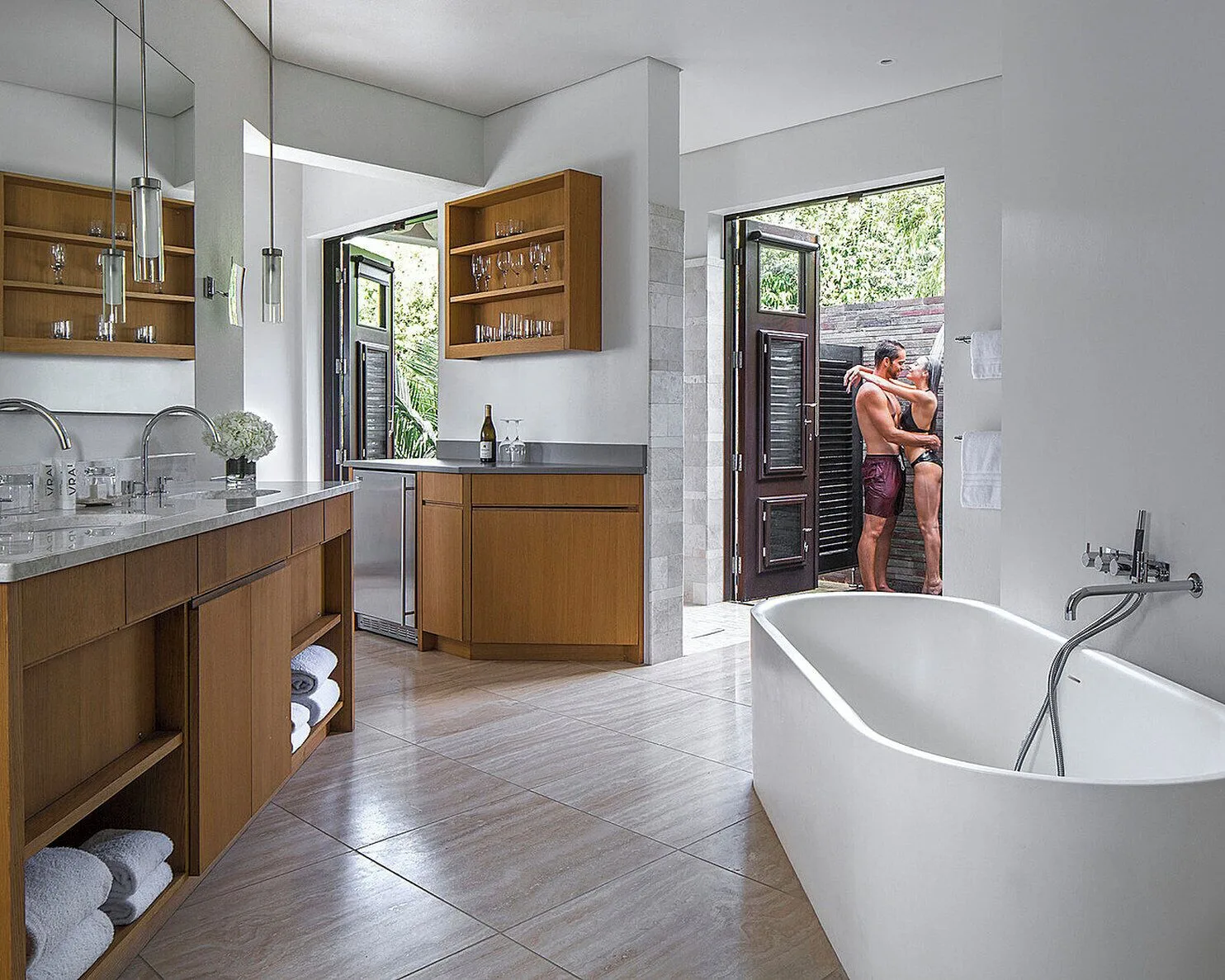 Bathroom with tub, vanity and open garden shower doors at Four Seasons Resort Nevis.