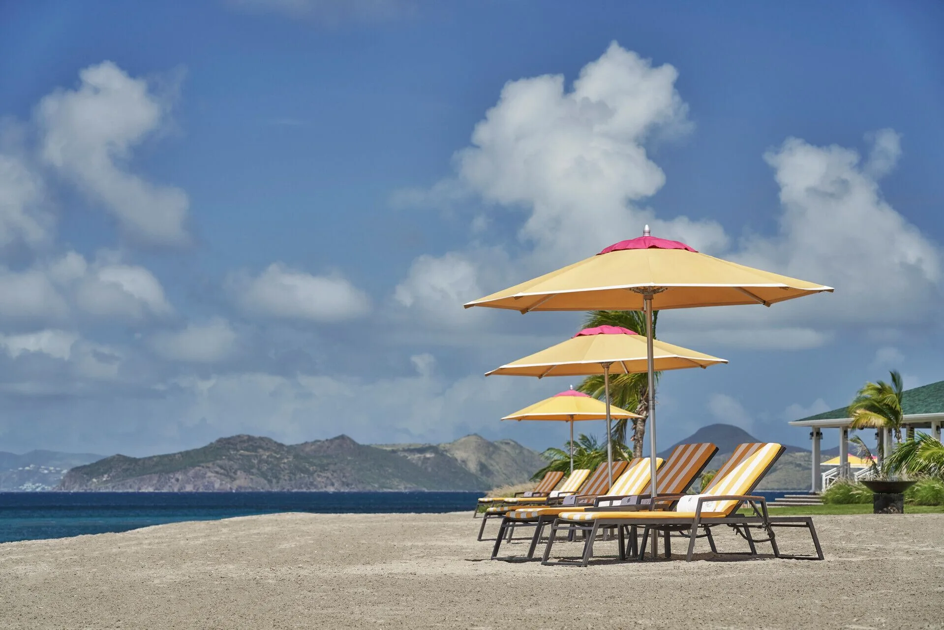 Beach loungers and yellow umbrellas facing the sea at Four Seasons Resort Nevis.