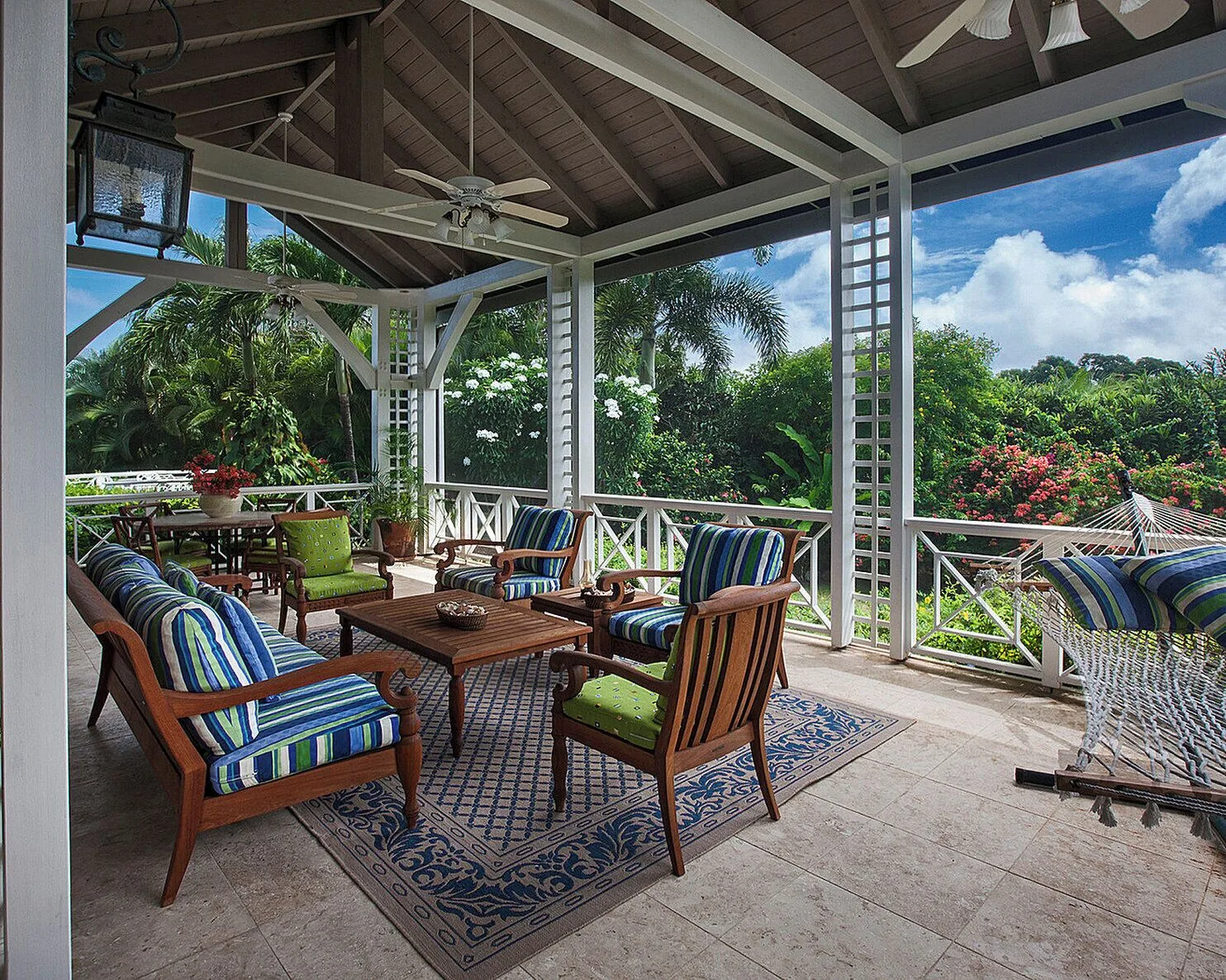 Covered terrace with striped seating and a hammock at Four Seasons Resort Nevis.