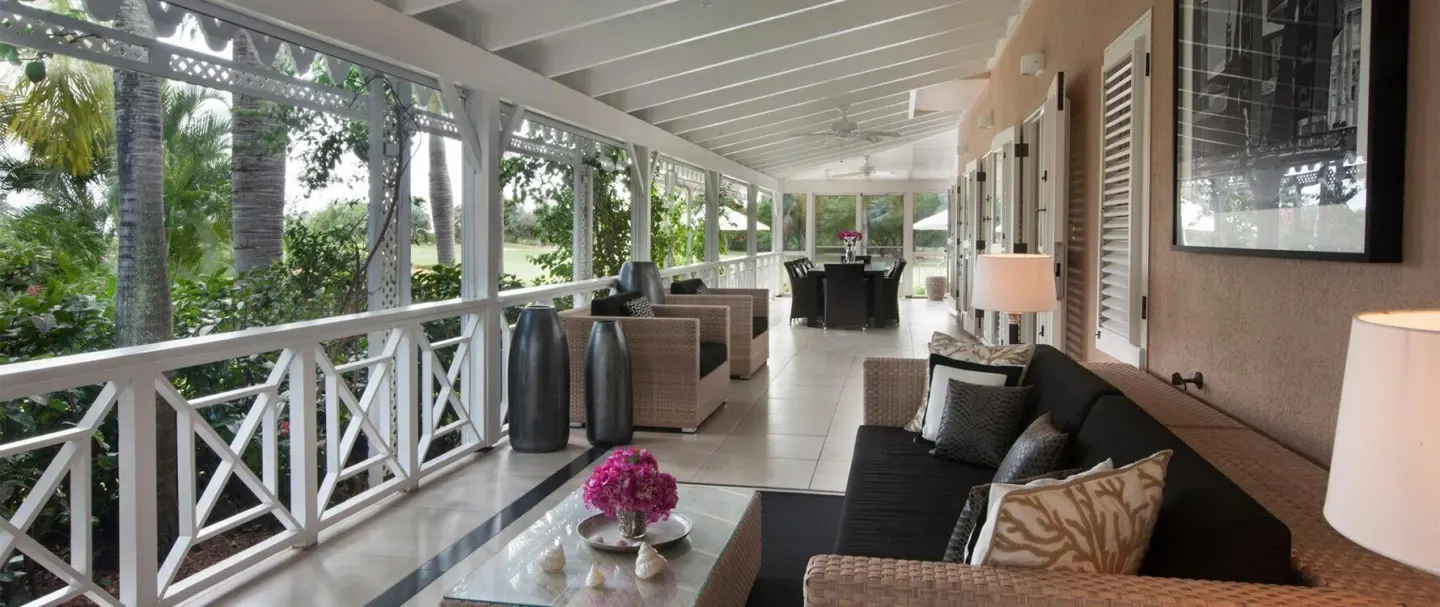 Covered veranda with sofas and tropical garden views at Four Seasons Resort Nevis.