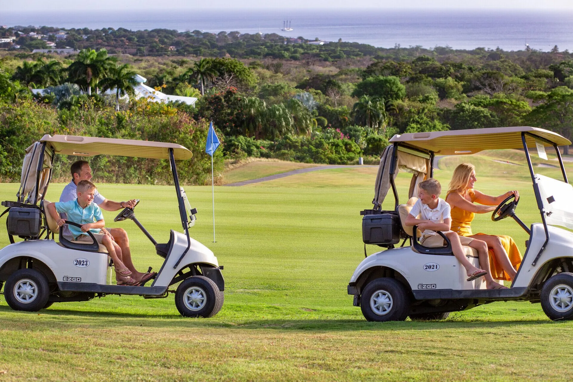 Families ride golf carts across a green fairway at Four Seasons Resort Nevis.