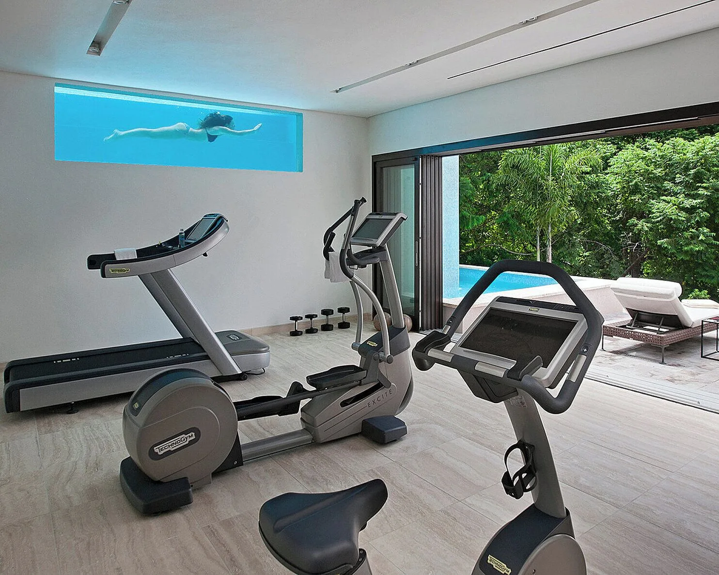 Fitness room with cardio equipment beside a pool at Four Seasons Resort Nevis.