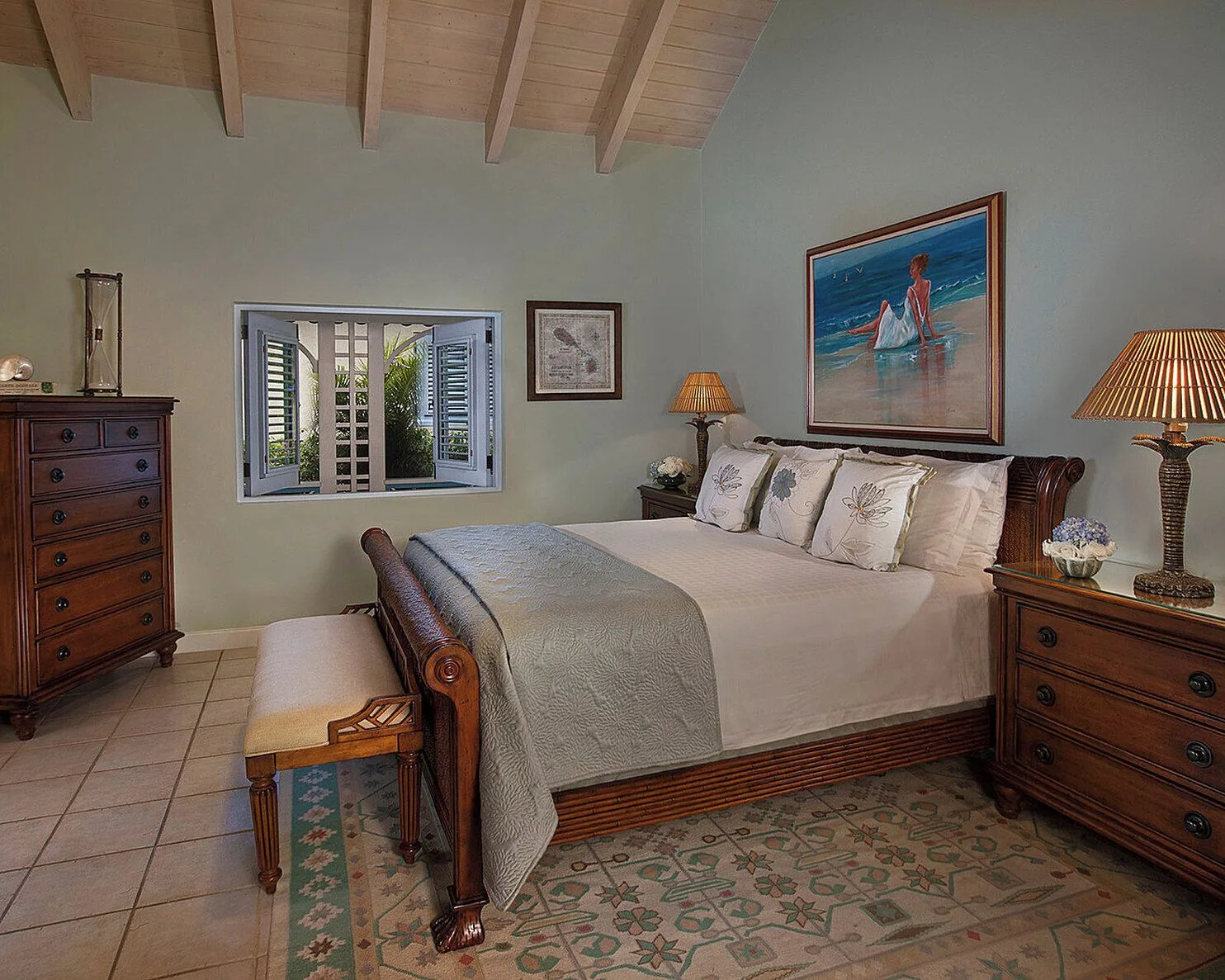 Guest bedroom with a wood bed and tropical artwork at Four Seasons Resort Nevis.