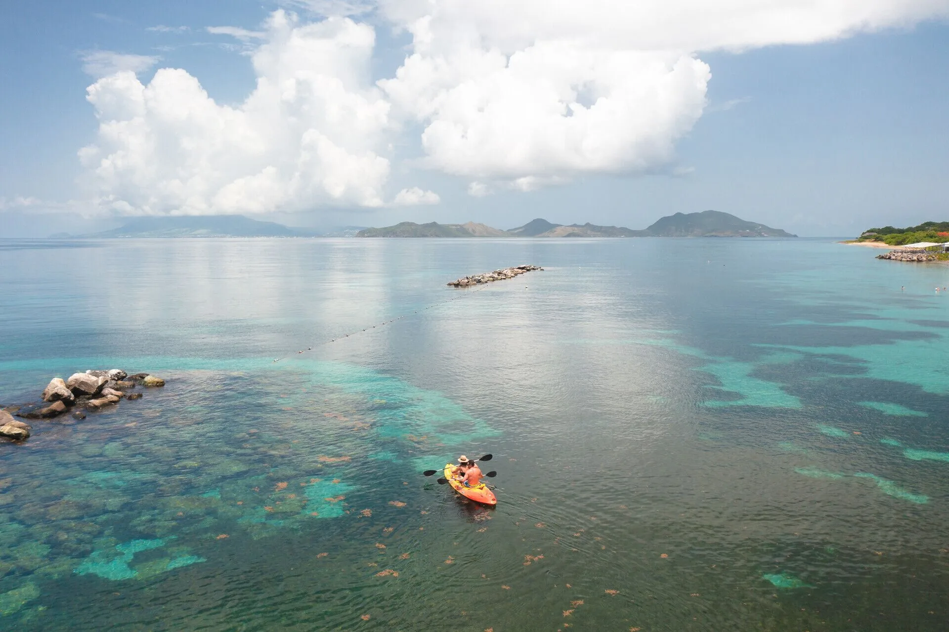 A kayaker paddles over clear Caribbean water at Four Seasons Resort Nevis.