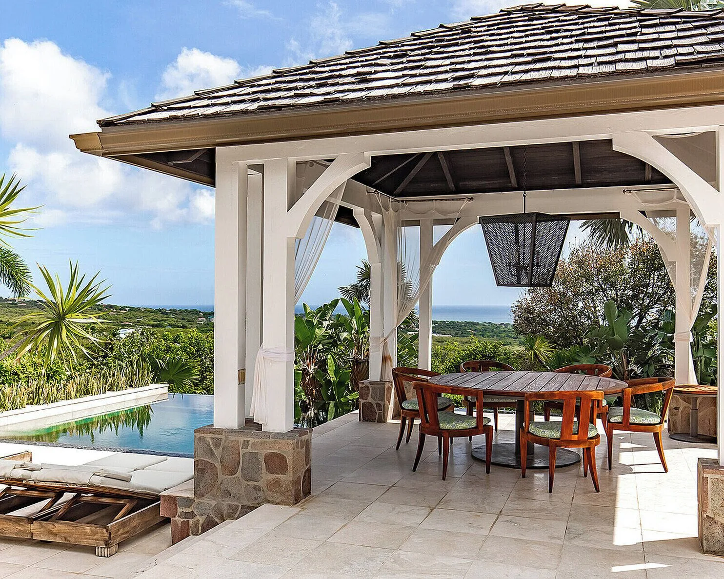 Open-air dining pavilion with pool and ocean view at Four Seasons Resort Nevis.