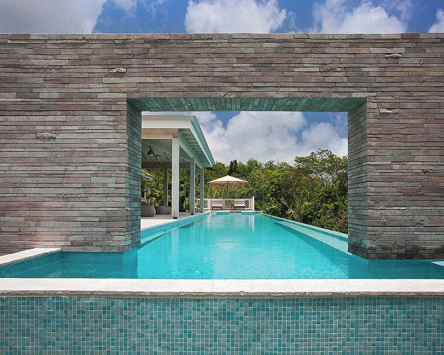 Pool framed by a stone wall opening at Four Seasons Resort Nevis.