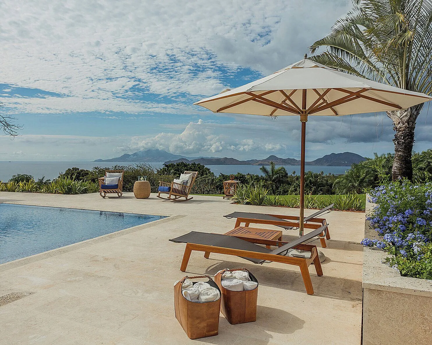 Pool terrace with loungers, umbrella and island views at Four Seasons Resort Nevis.