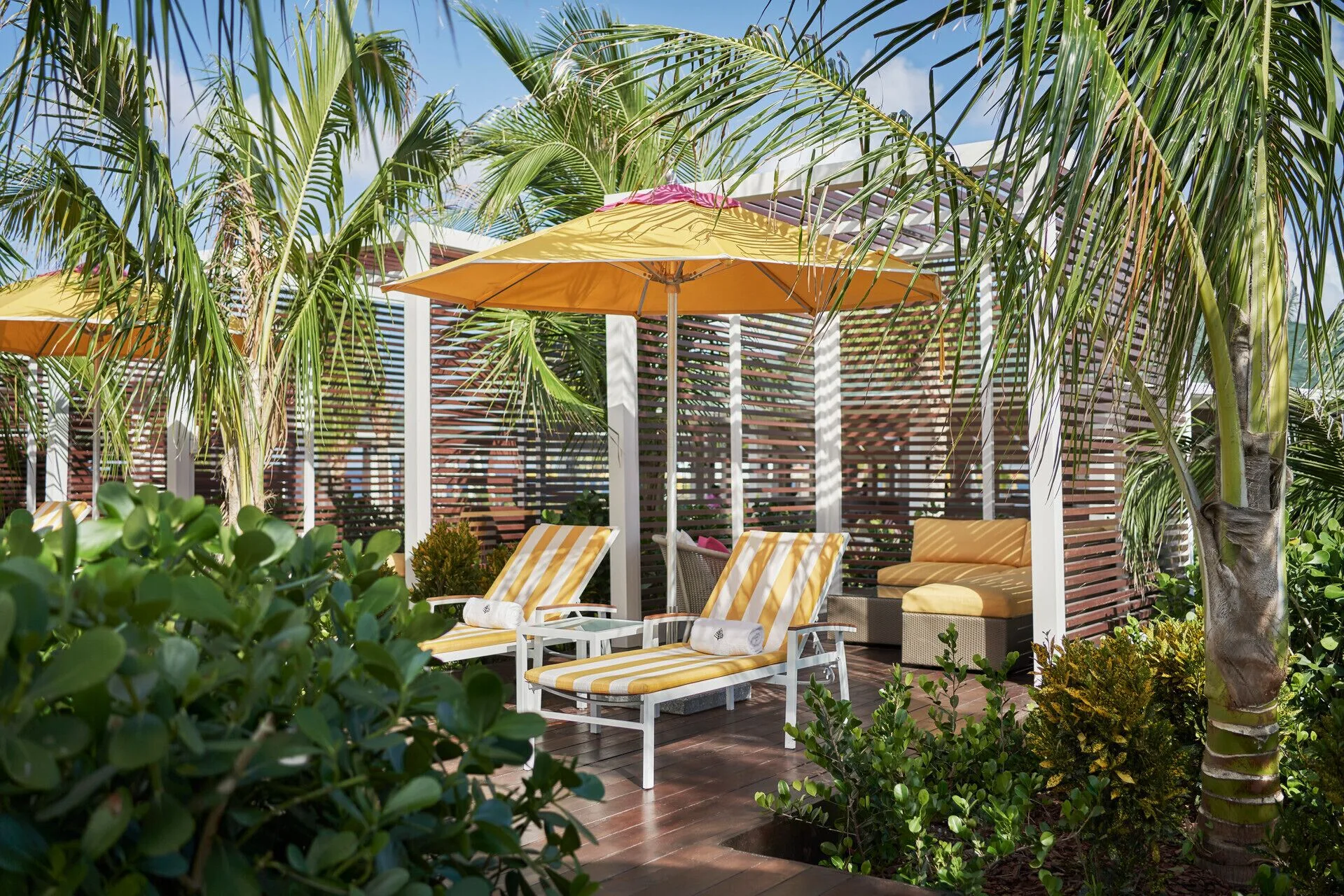 Yellow-striped loungers under palms in a cabana at Four Seasons Resort Nevis.