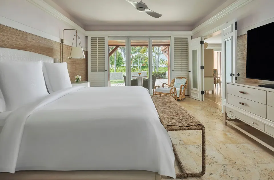 Kalinago Suite king bedroom with terrace doors and TV at Four Seasons Resort Nevis.