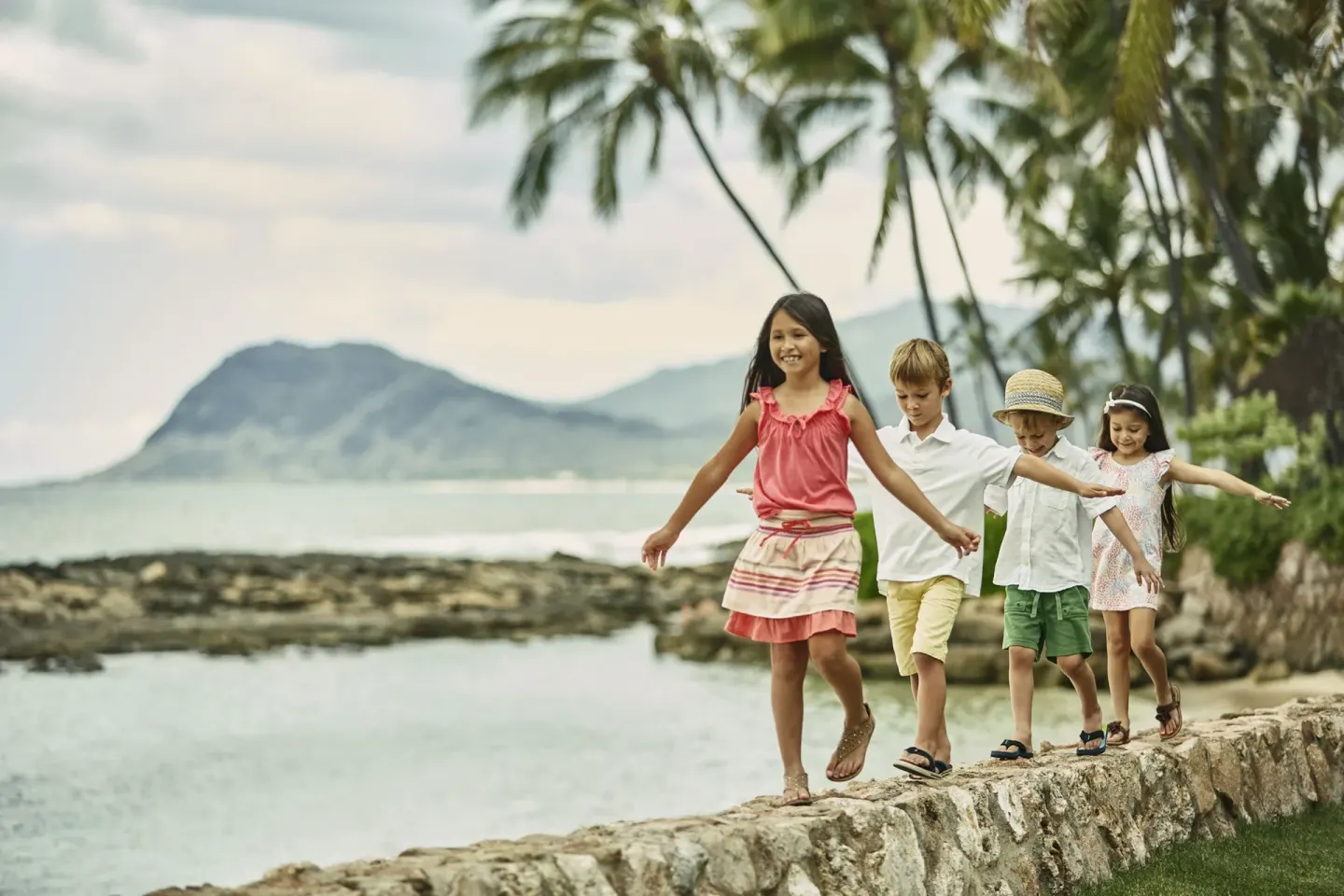 Children walking along a stone seawall at Four Seasons Resort Oahu at Ko Olina.