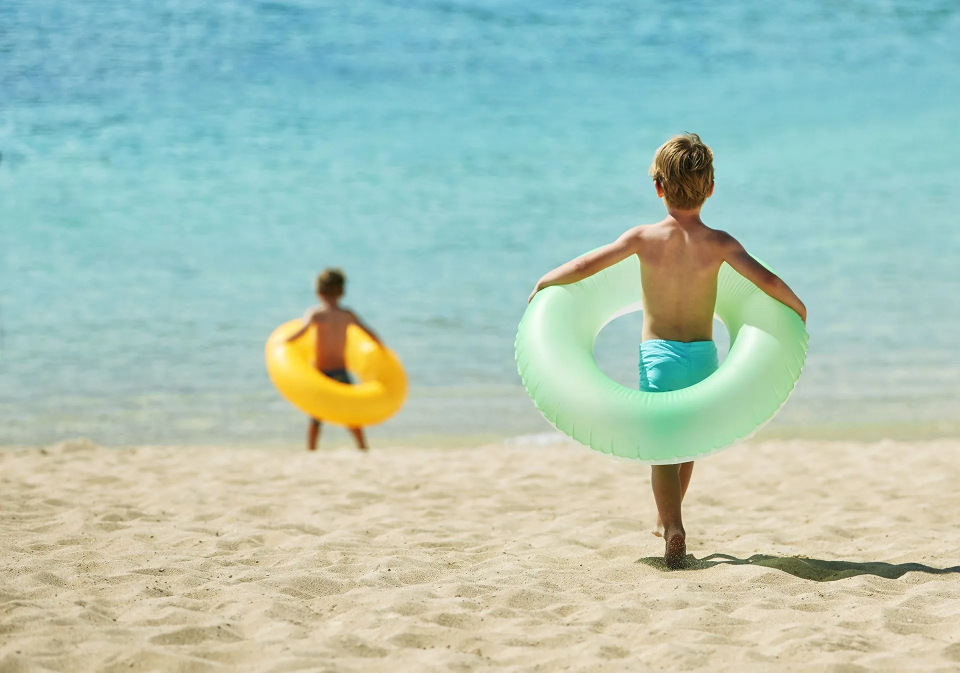 Children carrying swim rings toward the lagoon at Four Seasons Resort Oahu at Ko Olina.